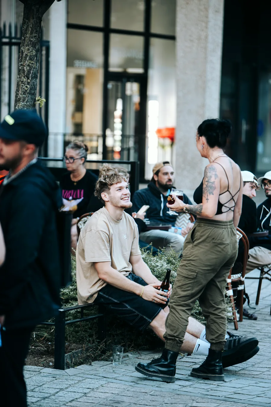 Terrasse en fin de journée : un client attablé, une serveuse qui passe entre les tables