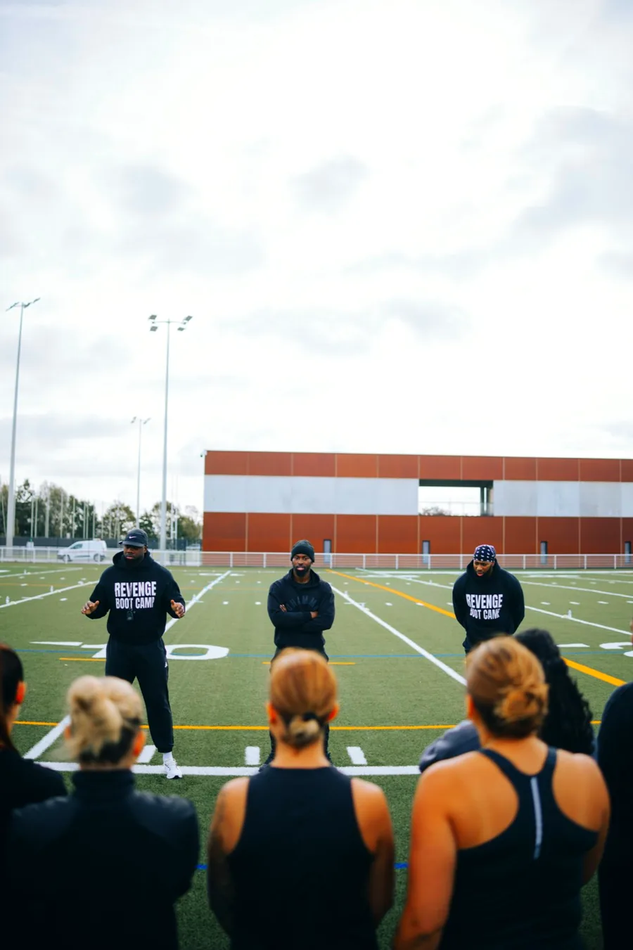 Briefing d'avant-séance : trois coachs face au groupe, au milieu du terrain