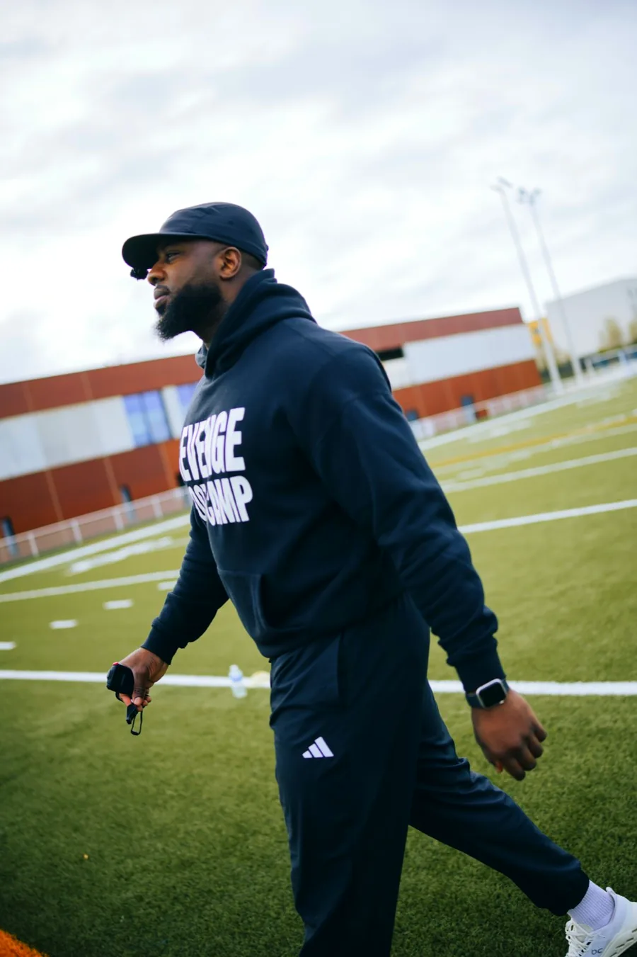 Coach traversant le terrain, chronomètre à la main